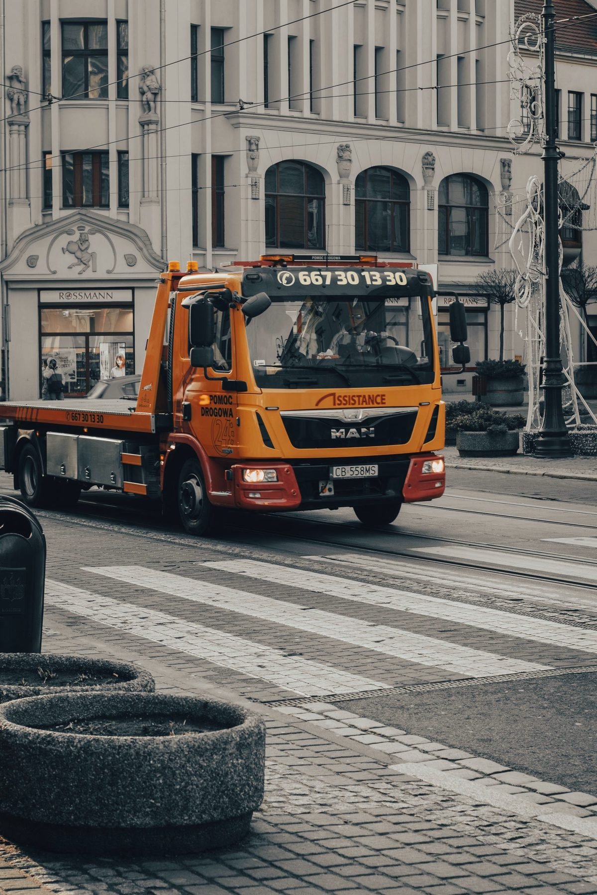 A yellow flatbed carrier driving through a city street