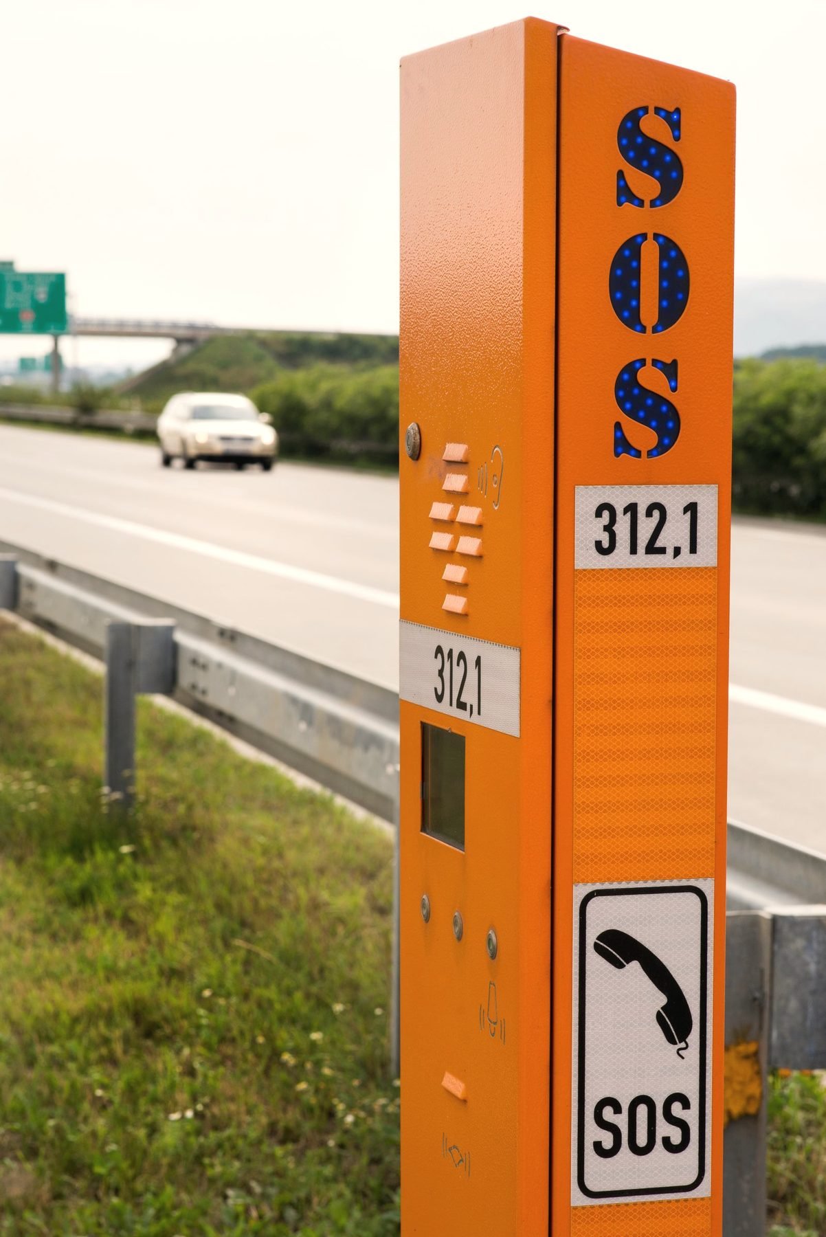 An orange roadside SOS emergency call phone beside a motorway
